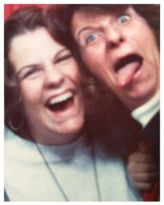 The author, as a teenager, laughs with her mother in a photo booth. Her mother is making a funny face and sticking out her tounge.