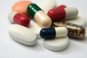 Close up of different pills laid out on a white countertop