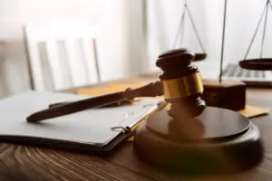 Stock image features a wooden desk with a gavel, paper stacked, and balance beam in the background